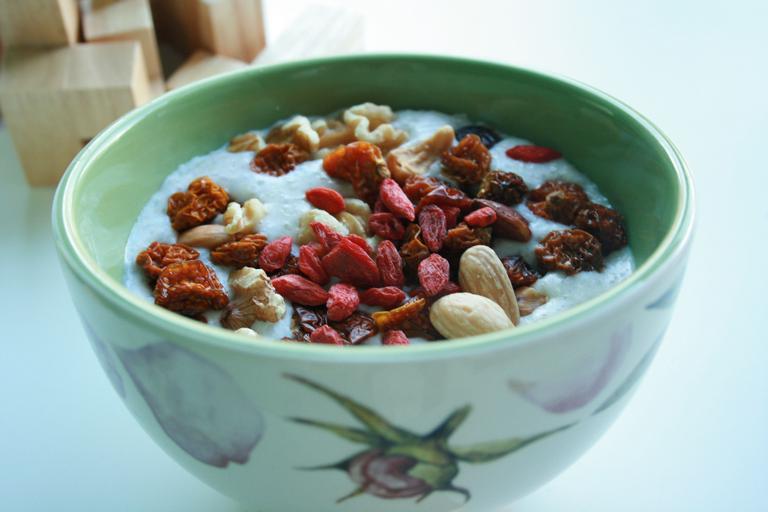 zdravá snídaně – miska s kaší a posypaná zdravými surovinami – včetně mandlí
